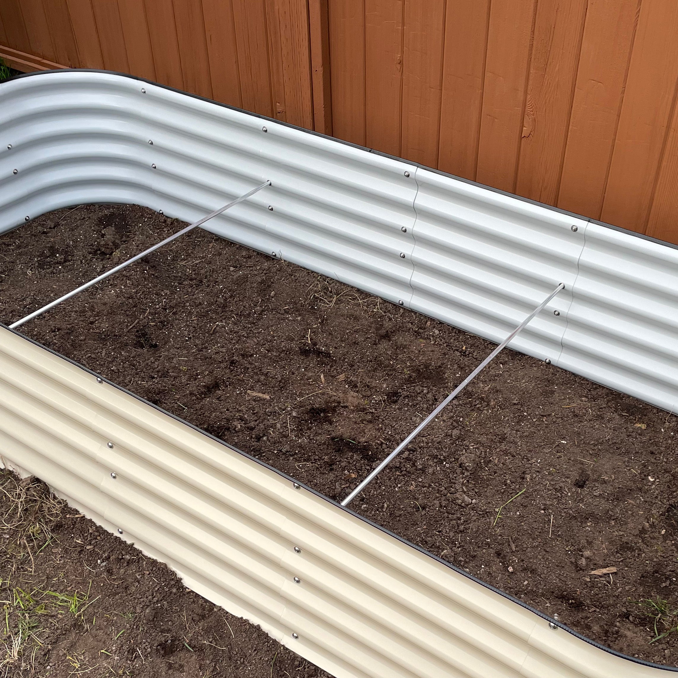 Aluminum bracing rod installed inside raised garden bed for structural support